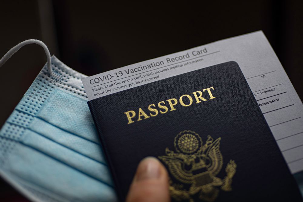 Blurred COVID-19 Vaccination Record card, Passport of USA and Medical Mask for travel concept.