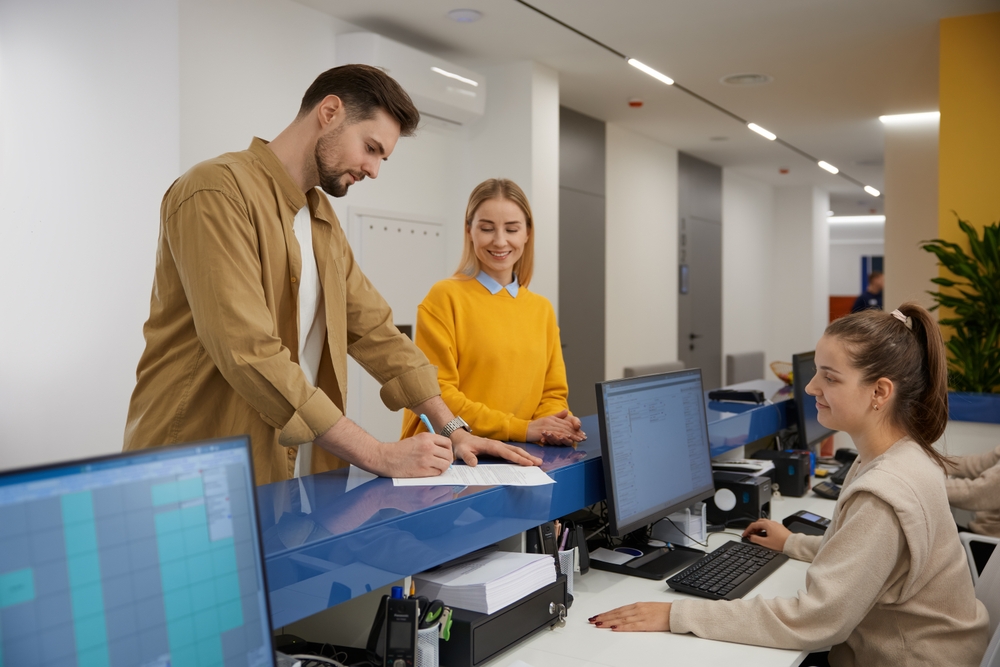 Man and woman couple signing document at modern clinic reception desk