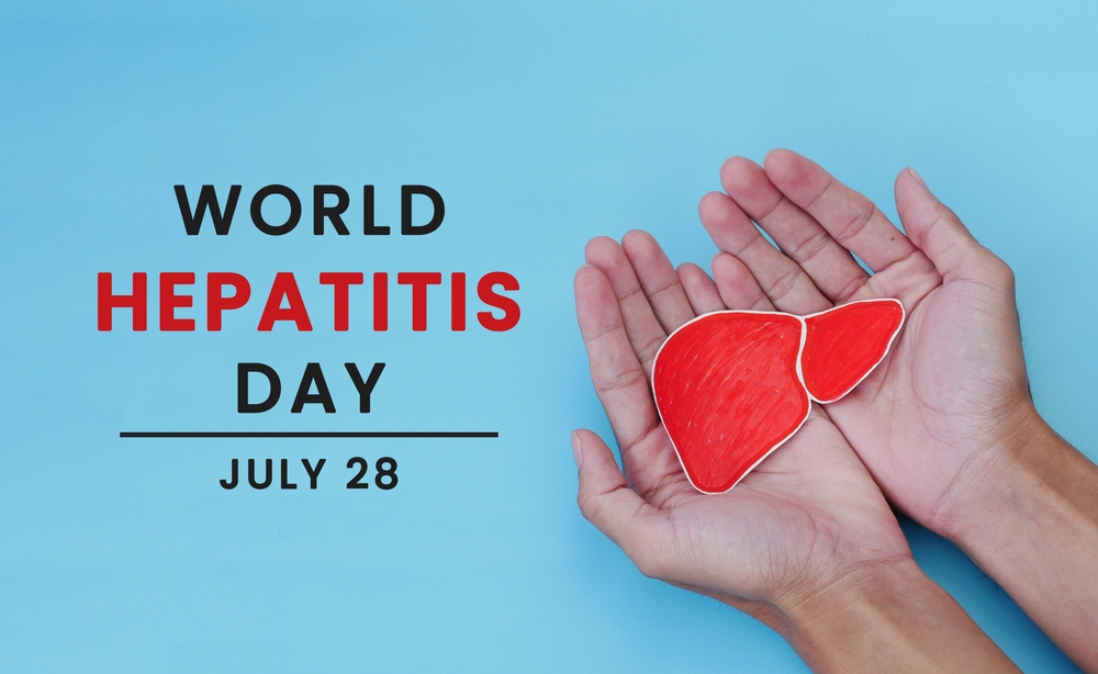 World Hepatitis Day on July 28. Man's hand holding paper heart symbol on light blue background. Concept of heart donation, prevention and treatment of viral hepatitis. Heart cancer.